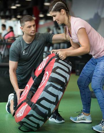 The Academy - Level 3 PT & FI Coach instructing a member on wheel flip exercise