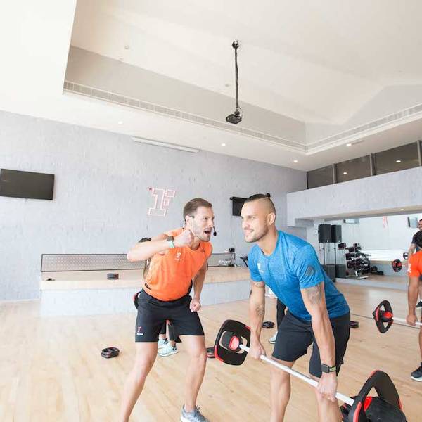Trainer motivating trainee performing dead-lift exercise Trainer motivating trainee performing dead-lift exercise
