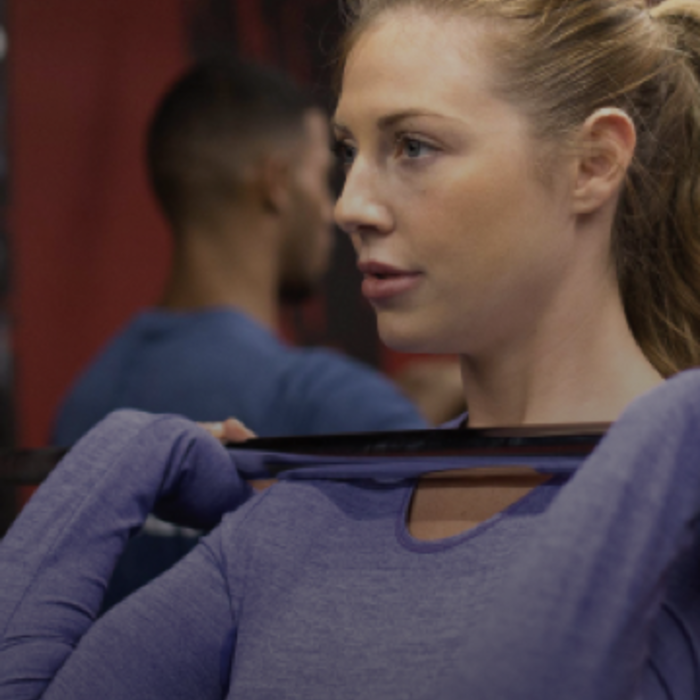 Kube Wall Female Fitness First member lifting weight barbell